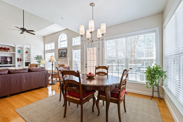 dining space featuring baseboards, light wood finished floors, and ceiling fan with notable chandelier