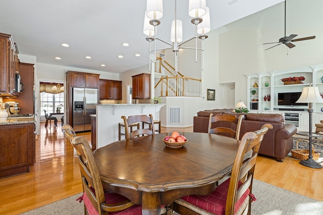 dining area featuring light wood-style flooring, recessed lighting, ceiling fan with notable chandelier, visible vents, and stairs