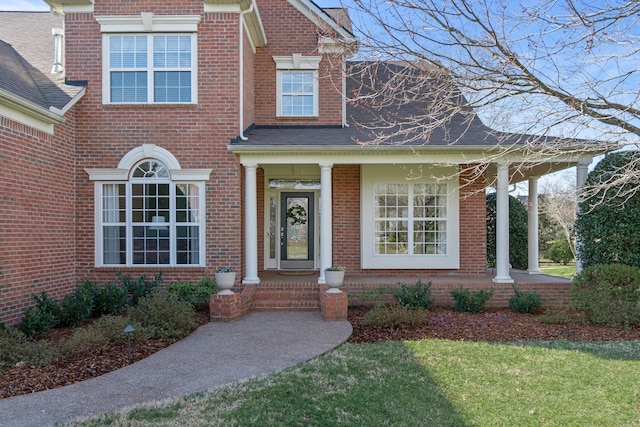 view of front of home with roof with shingles and brick siding