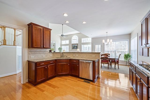 kitchen featuring light stone counters, a peninsula, stainless steel dishwasher, light wood finished floors, and tasteful backsplash