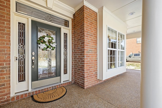 entrance to property featuring a porch and brick siding