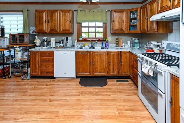 kitchen with brown cabinets, white dishwasher, range with two ovens, and a sink