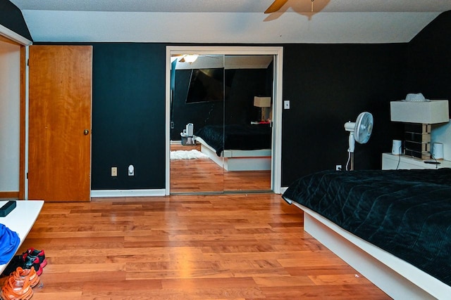 bedroom with a ceiling fan, a closet, light wood-style flooring, and baseboards