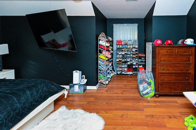 bedroom featuring a textured ceiling, wood finished floors, visible vents, and baseboards