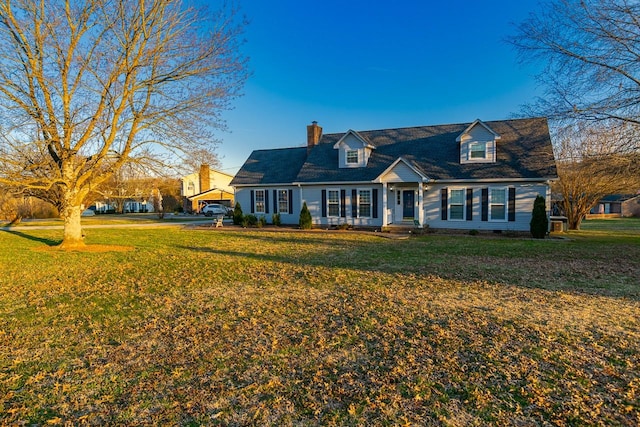 new england style home featuring a chimney and a front lawn