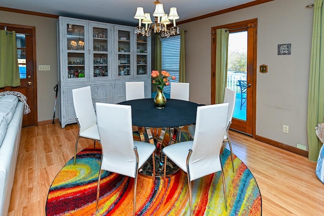 dining space featuring light wood-style floors, baseboards, crown molding, and an inviting chandelier