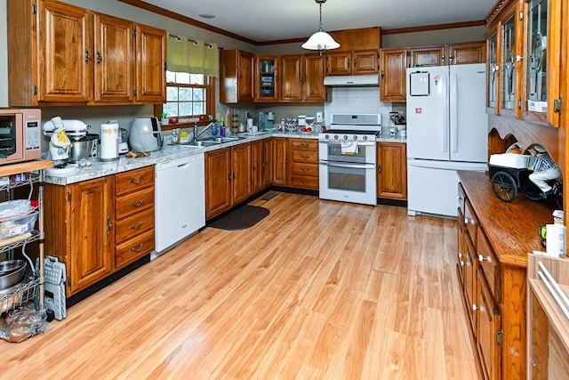 kitchen with light wood-style flooring, under cabinet range hood, white appliances, brown cabinetry, and crown molding