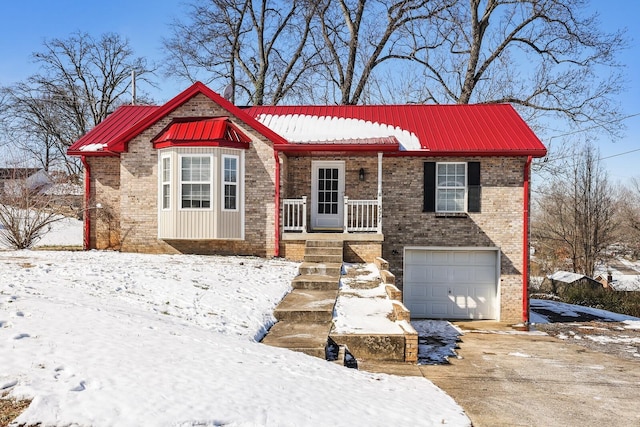 view of front of home with driveway, an attached garage, metal roof, and brick siding