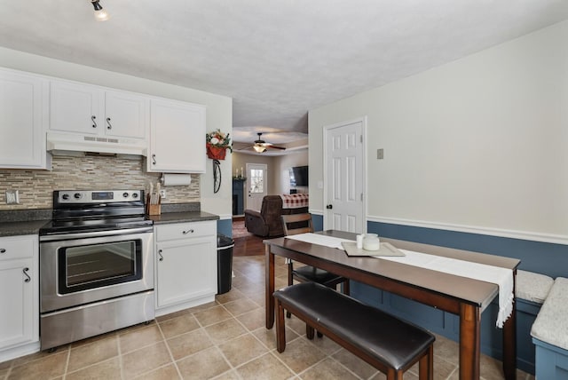 kitchen featuring tasteful backsplash, dark countertops, stainless steel range with electric stovetop, and under cabinet range hood