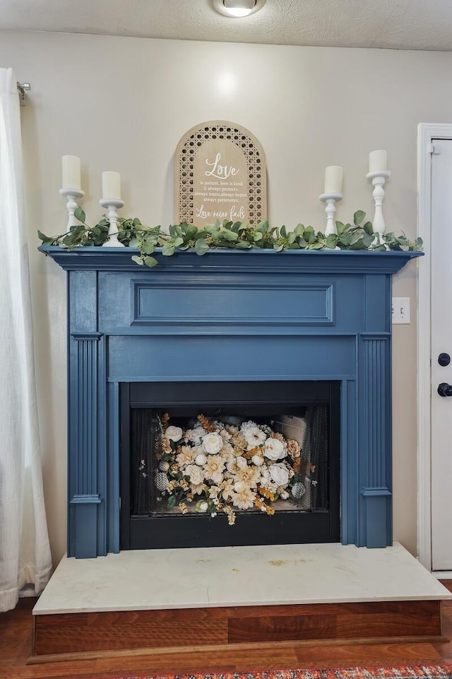 details featuring a fireplace with raised hearth and a textured ceiling