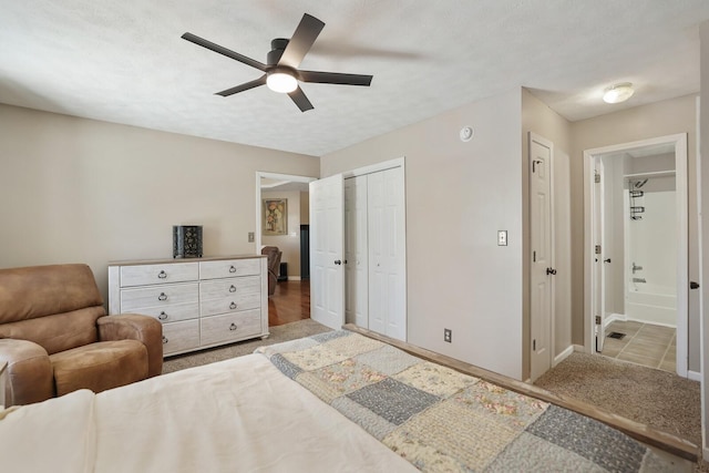 carpeted bedroom featuring a closet, ceiling fan, a textured ceiling, ensuite bath, and baseboards