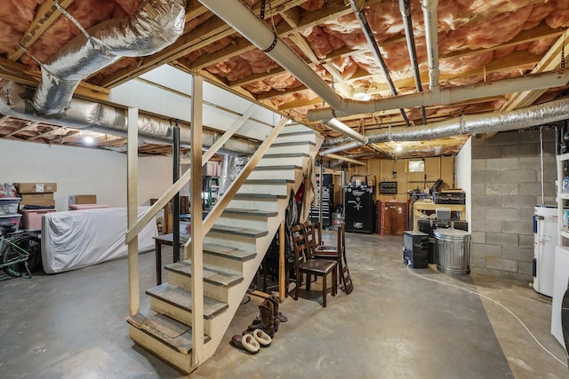 unfinished basement featuring concrete block wall, water heater, and stairway