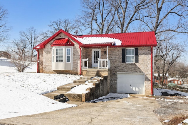 view of front facade featuring driveway, an attached garage, metal roof, and brick siding