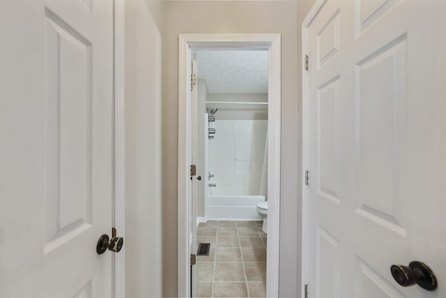 corridor featuring a textured ceiling and light tile patterned floors