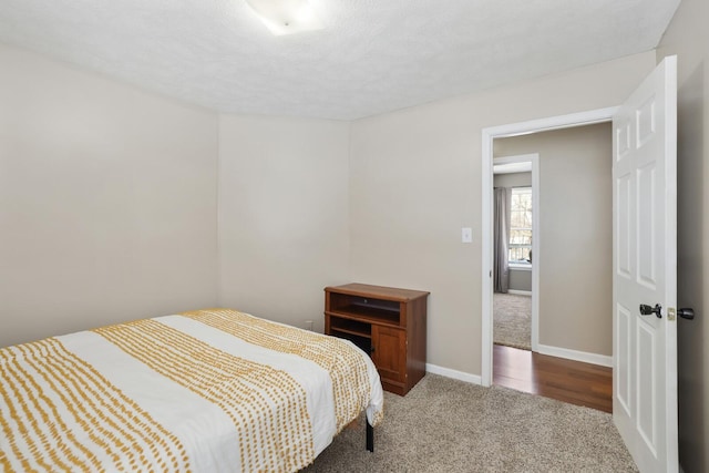 carpeted bedroom featuring a textured ceiling and baseboards