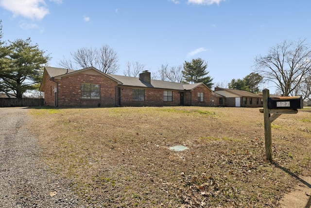 ranch-style house with brick siding, a chimney, and a front lawn