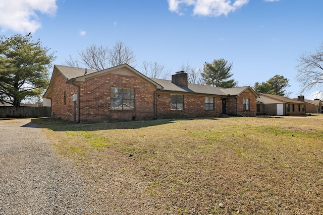 ranch-style house featuring driveway, a chimney, fence, a front lawn, and brick siding