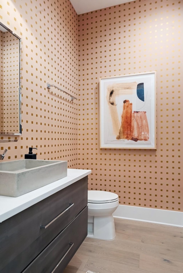 half bath featuring toilet, wood finished floors, and vanity