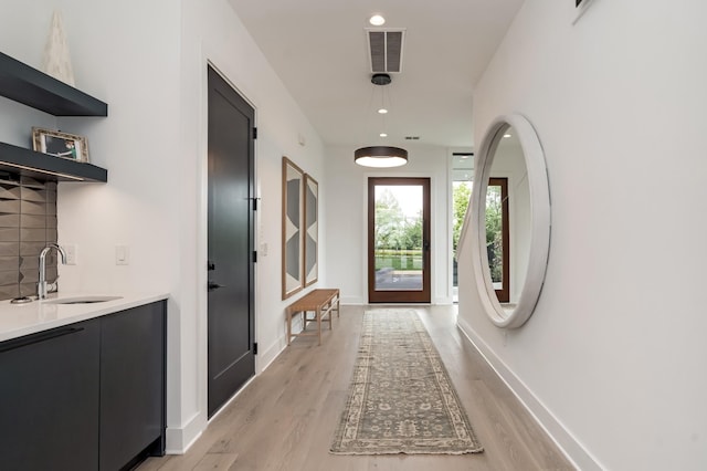 interior space featuring recessed lighting, a sink, visible vents, baseboards, and light wood-style floors