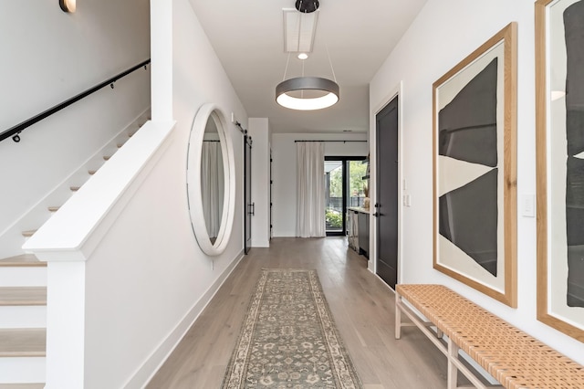 hall with light wood-style floors, baseboards, and stairway