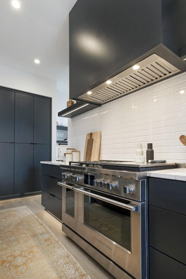 kitchen with range with two ovens, decorative backsplash, modern cabinets, custom exhaust hood, and light countertops