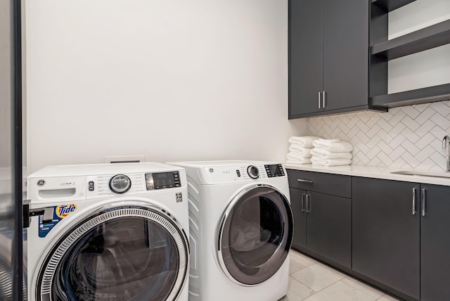 washroom with light tile patterned flooring, independent washer and dryer, a sink, and cabinet space