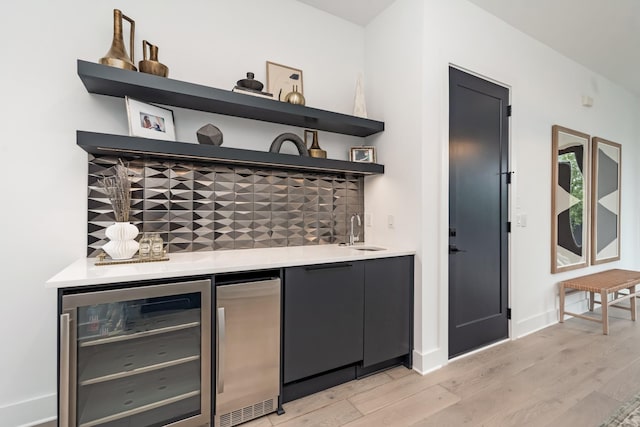 bar with decorative backsplash, wine cooler, wet bar, fridge, and a sink