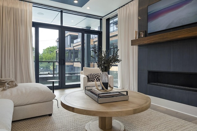 sitting room featuring recessed lighting, a large fireplace, wood finished floors, french doors, and floor to ceiling windows