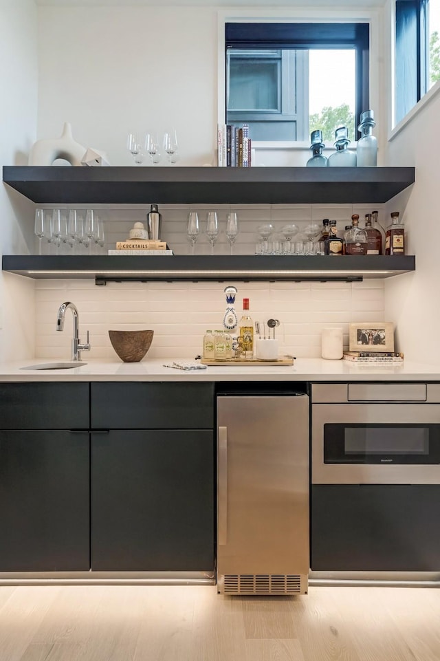 bar featuring refrigerator, backsplash, a sink, and wet bar