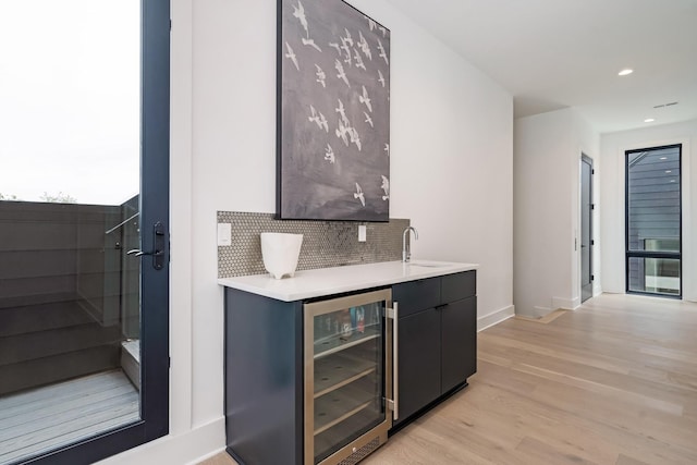 bar with recessed lighting, beverage cooler, a sink, backsplash, and light wood finished floors