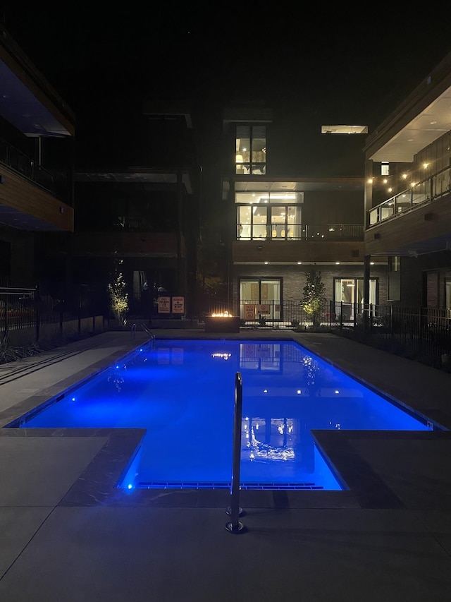 pool at twilight featuring a patio, fence, and a fenced in pool