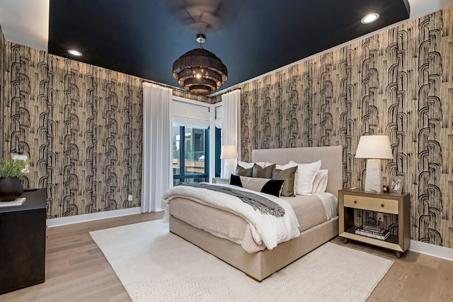 bedroom featuring access to outside, wood finished floors, baseboards, and wallpapered walls