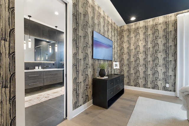 full bathroom with wallpapered walls, baseboards, wood finished floors, vanity, and recessed lighting