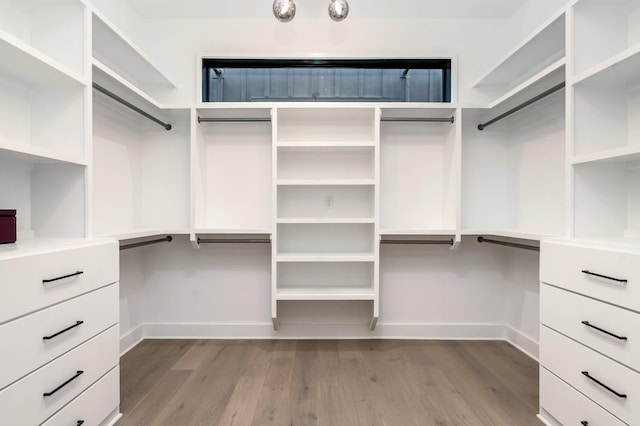 walk in closet featuring built in desk and wood finished floors