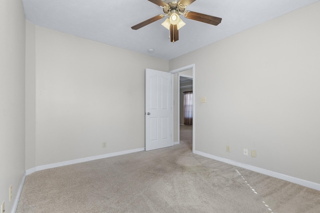 carpeted spare room with baseboards and ceiling fan