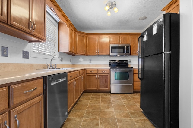 kitchen with light countertops, brown cabinets, appliances with stainless steel finishes, and a sink