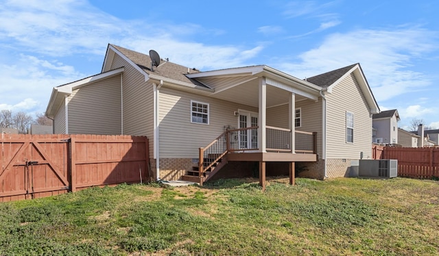 rear view of property featuring a gate, central AC unit, a lawn, and fence