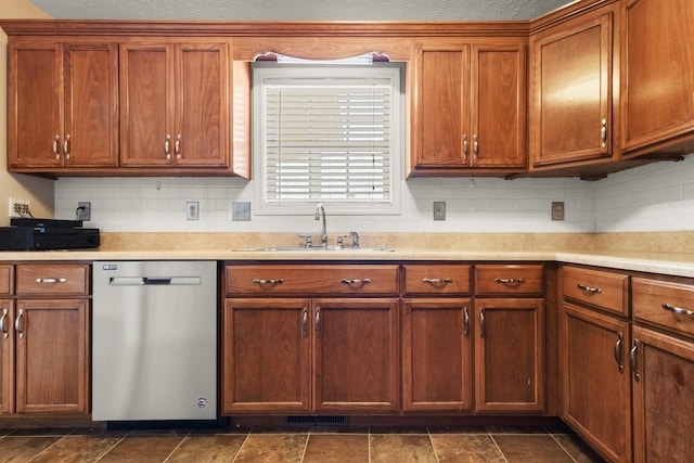 kitchen with stainless steel dishwasher, light countertops, brown cabinets, and a sink