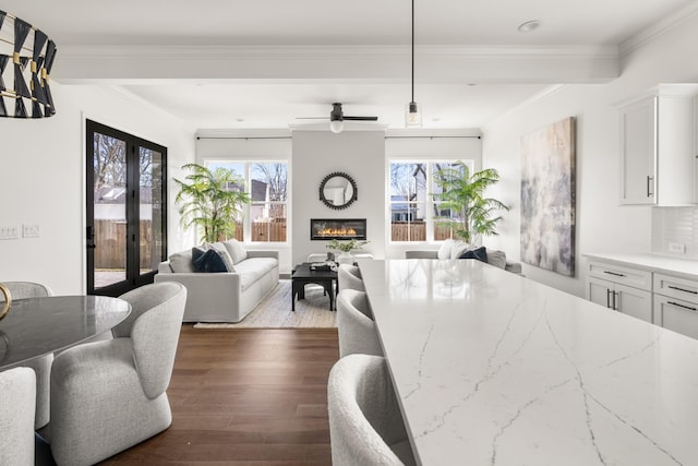 dining space featuring dark wood-style floors, french doors, ornamental molding, and a fireplace