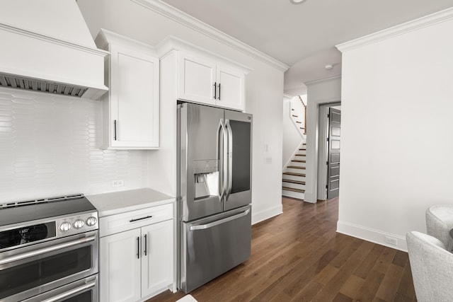 kitchen with dark wood-style flooring, white cabinetry, ornamental molding, appliances with stainless steel finishes, and custom range hood