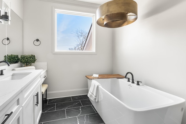 full bathroom with marble finish floor, baseboards, a freestanding tub, and vanity