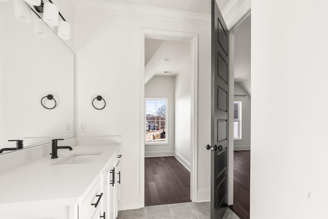 bathroom featuring ornamental molding, wood finished floors, vanity, and baseboards