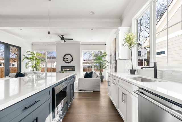 kitchen with a large fireplace, stainless steel appliances, a sink, open floor plan, and tasteful backsplash