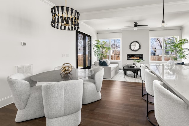 dining room with ornamental molding, a large fireplace, visible vents, and dark wood finished floors