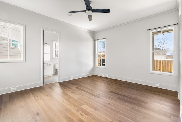 unfurnished bedroom with crown molding, light wood-style flooring, ceiling fan, ensuite bath, and baseboards