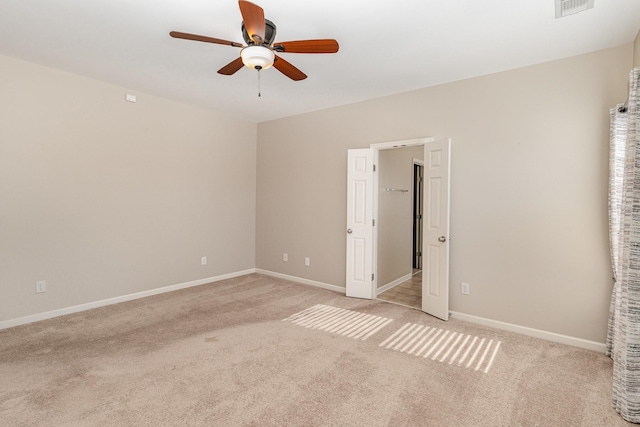 spare room with baseboards, visible vents, a ceiling fan, and light colored carpet