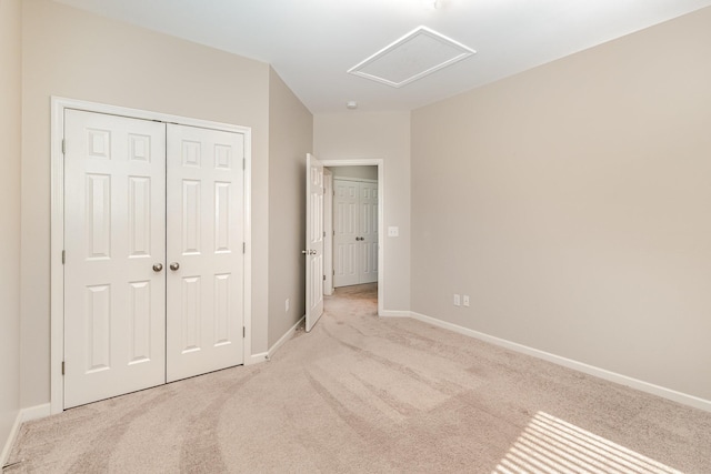 unfurnished bedroom featuring light carpet, attic access, baseboards, and a closet