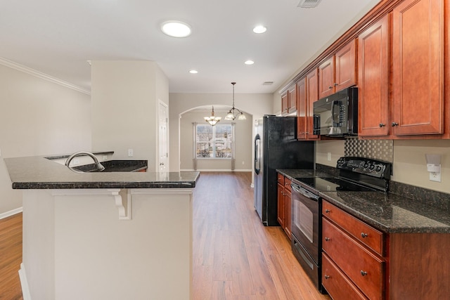 kitchen featuring arched walkways, baseboards, light wood-style flooring, a breakfast bar area, and black appliances