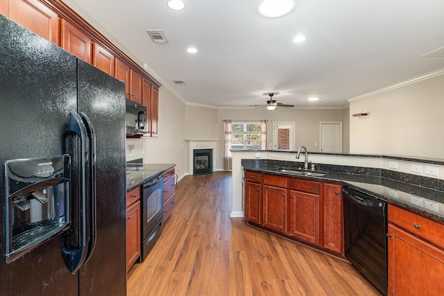 kitchen with light wood-style flooring, a sink, visible vents, black appliances, and crown molding