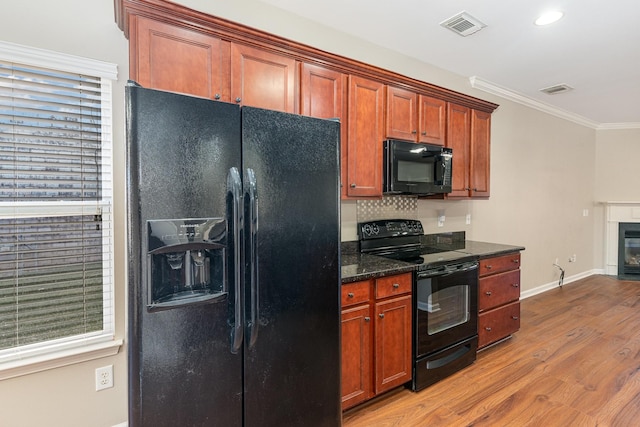 kitchen with baseboards, visible vents, ornamental molding, wood finished floors, and black appliances